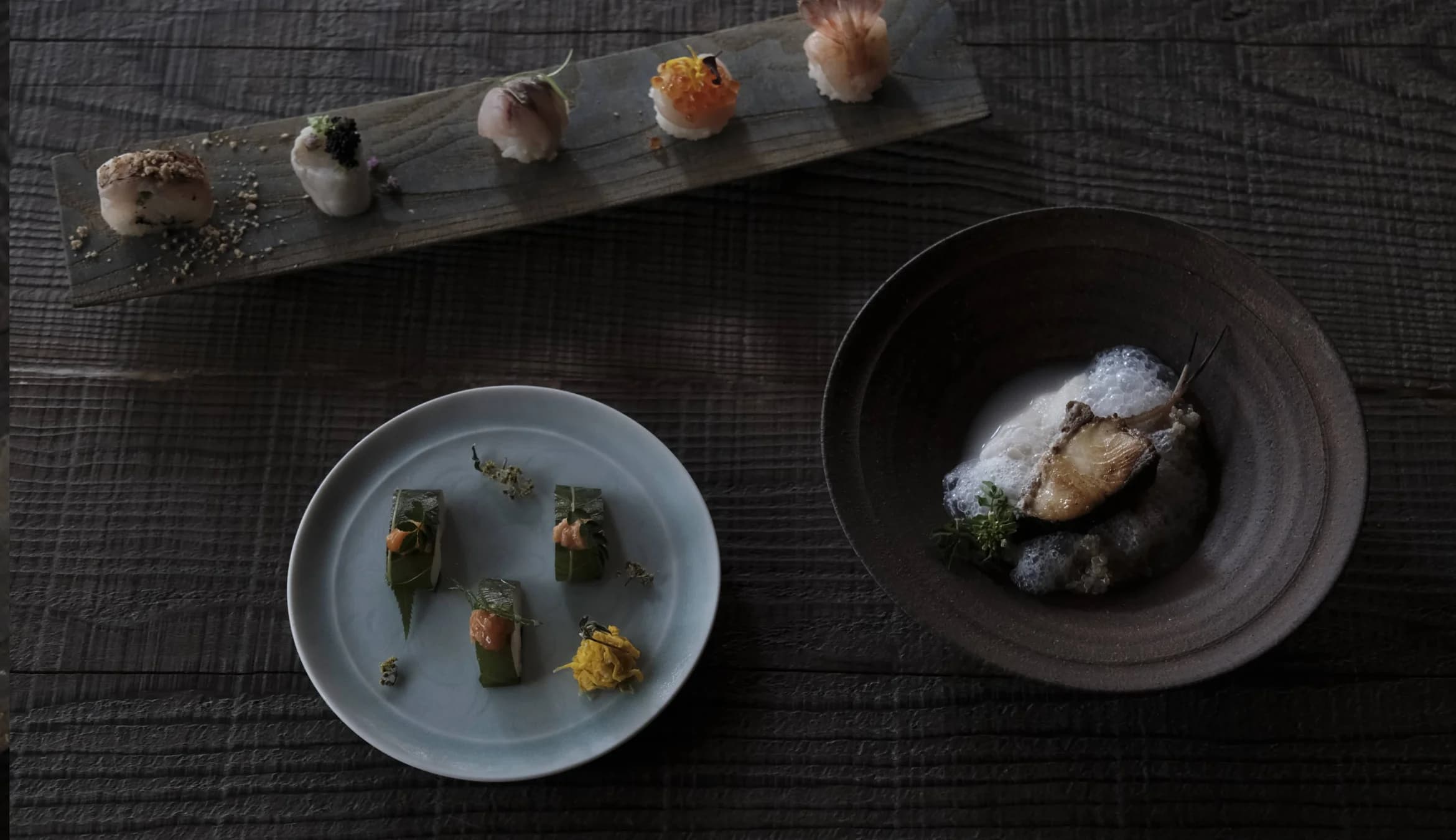 Small bites arranged on a wooden plank and in a bowl.