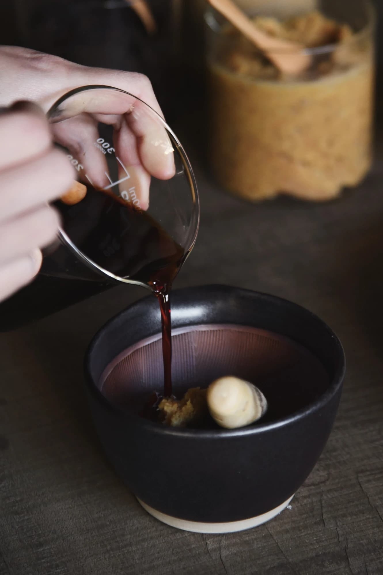 Chopsticks holding a pickled plum in a jar