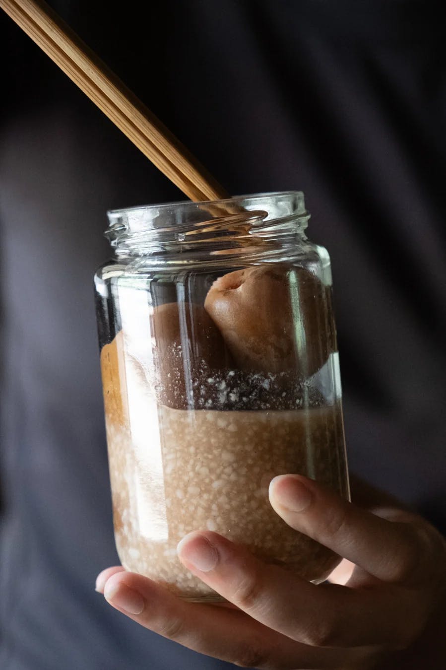 Chopsticks holding a pickled plum in a jar