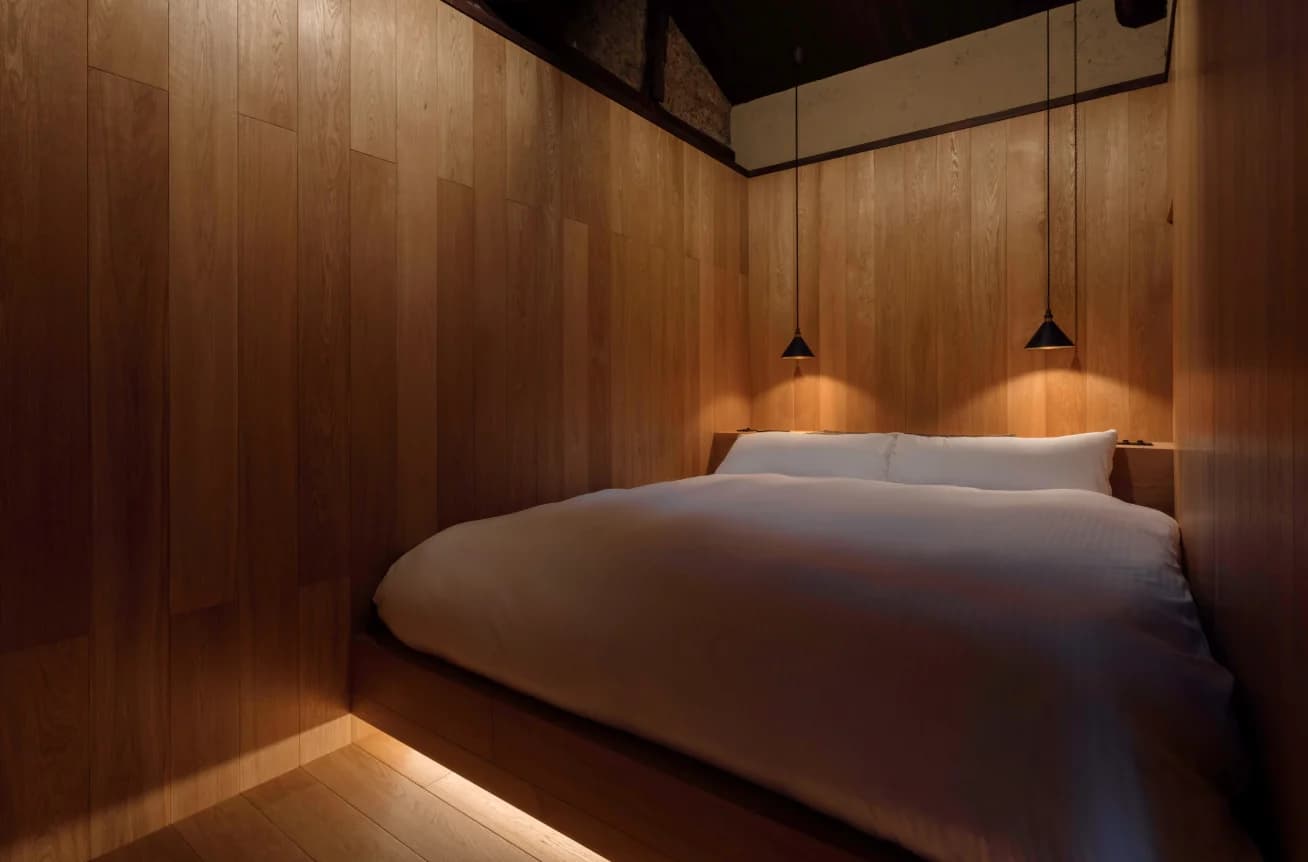 Bedroom with wood-paneled walls, platform bed, and pendant lights