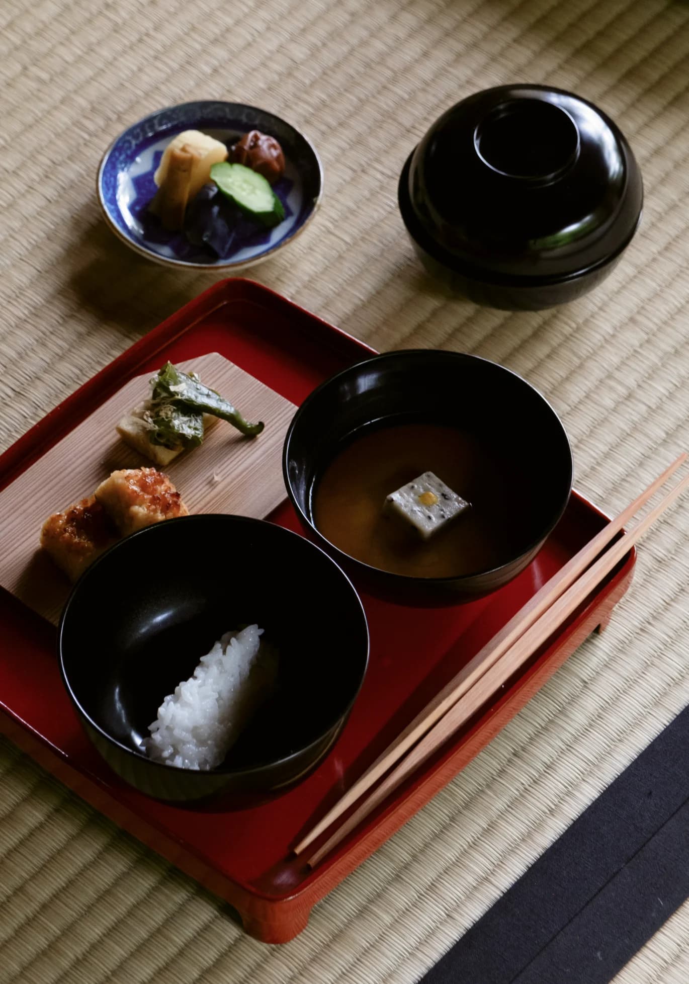 A tray with a traditional Japanese breakfast setting, including rice, soup, and pickled vegetables