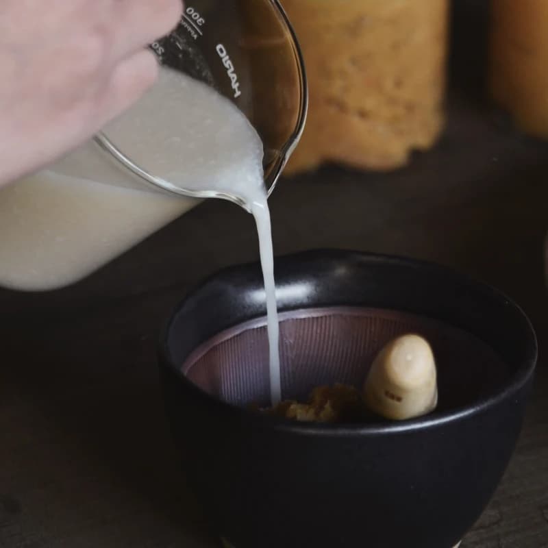 Pouring fermented amazake from a glass carafe