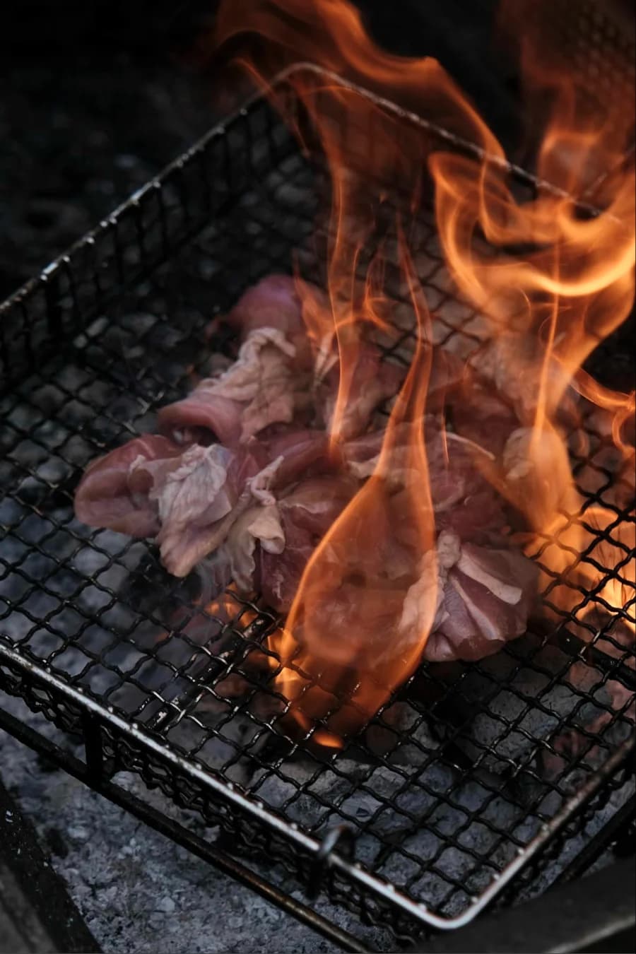 Chicken meat on a flaming charcoal grill