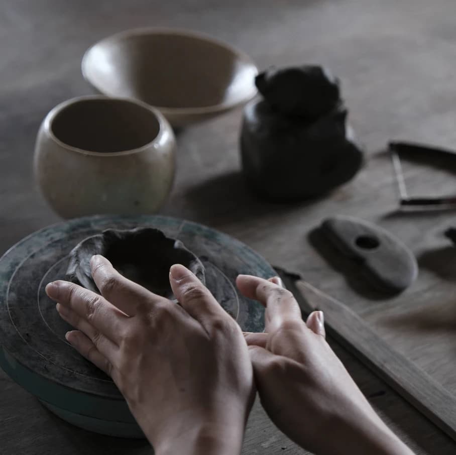 Potter's hands shaping clay on a wheel