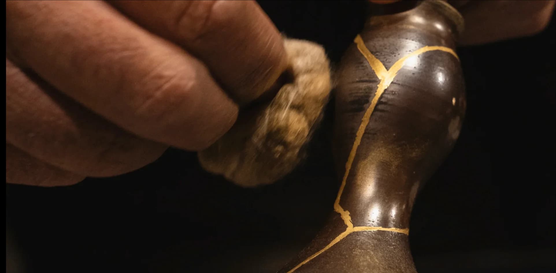 Close up of a hand polishing a ceramic piece repaired with gold kintsugi technique