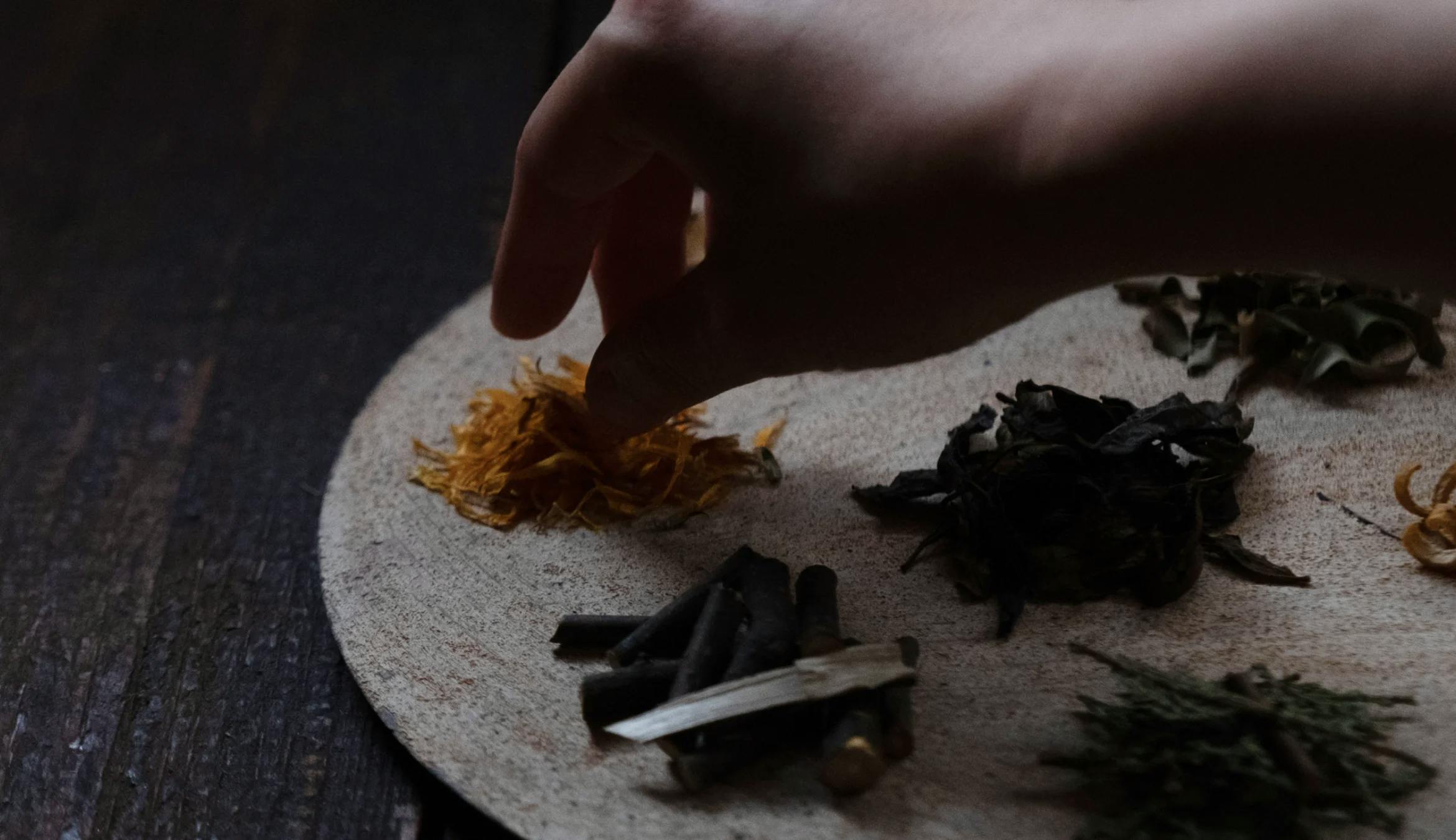 A hand touching a plate with flowers and tea