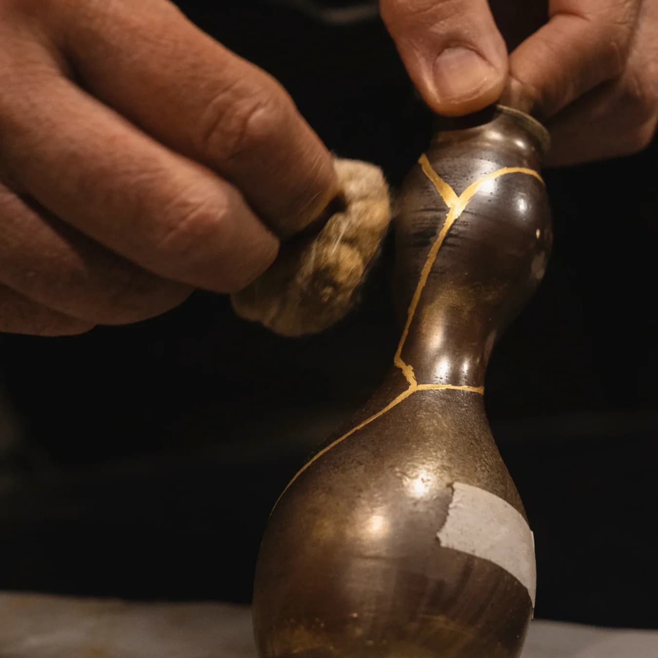 Close up of a hand polishing a ceramic piece repaired with gold kintsugi technique