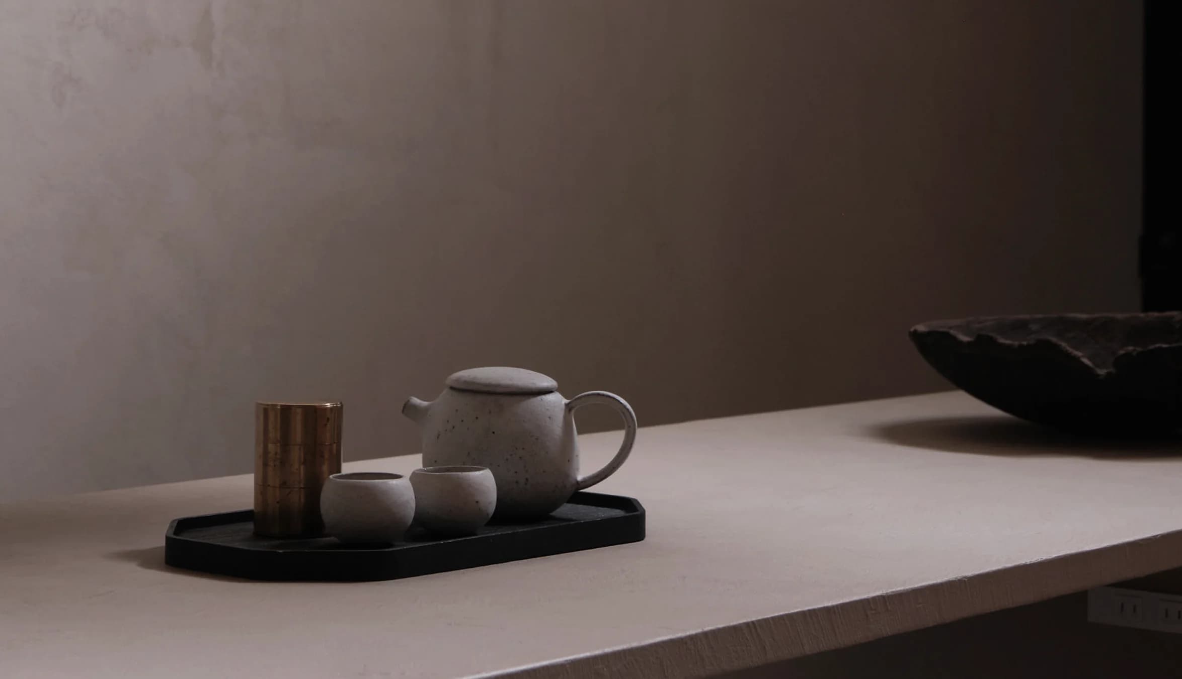 A clay teapot, tea cups, and a tea caddy on a tray.