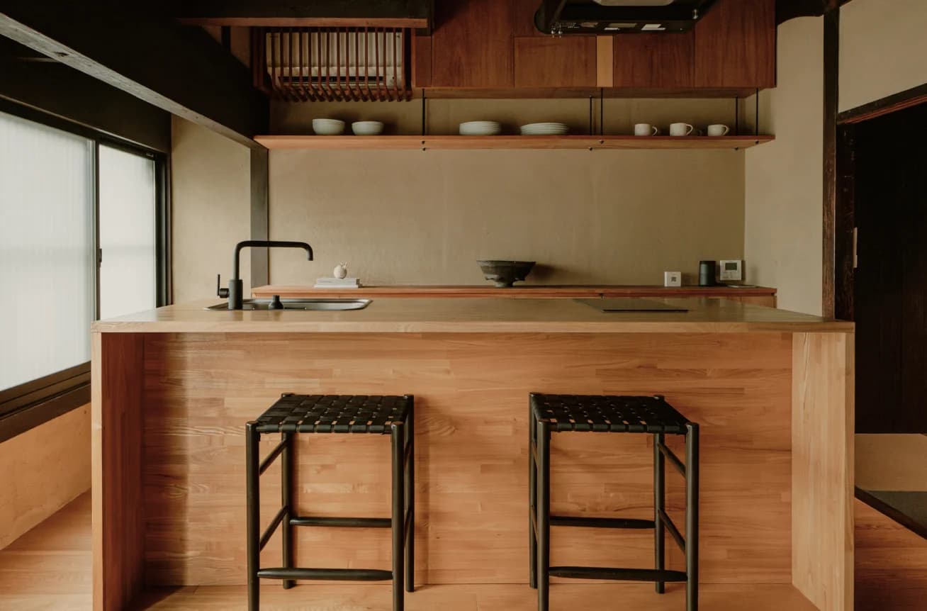 Kitchen island with wooden counter, bar stools, and open shelving